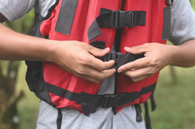Child buckling a red life jacket